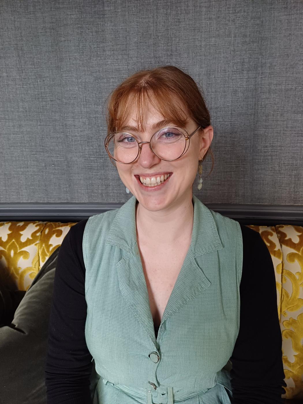 A woman with glasses smiles for the camera.