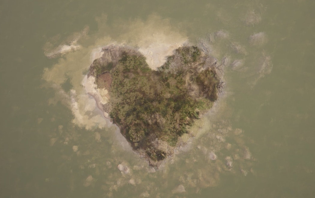 A heart-shaped island seen from above in a grey-green sea
