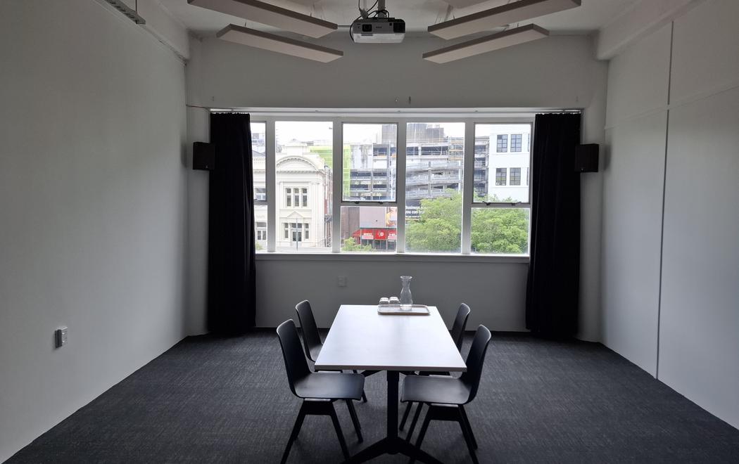 An empty gallery with a board room table. curtains and a view to the street