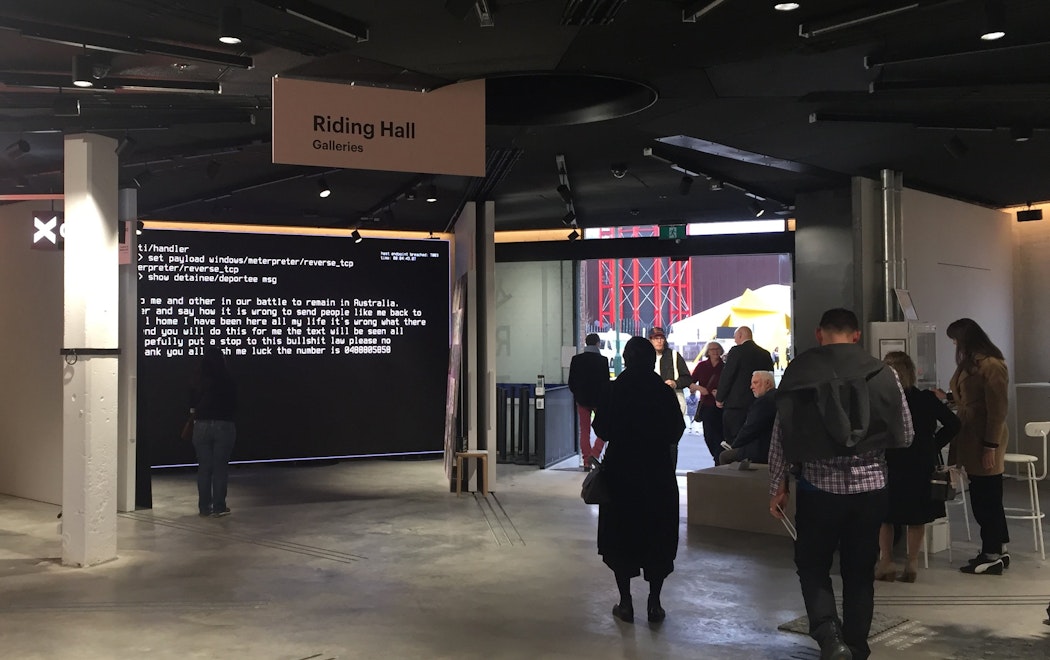 People move through a gallery space with concrete floors. Signage reads "riding hall galleries"