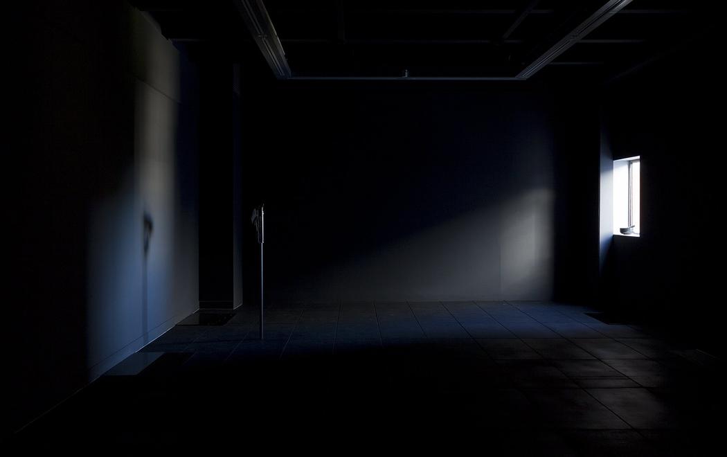 a dark room is lit from a small window in which the light leaks into