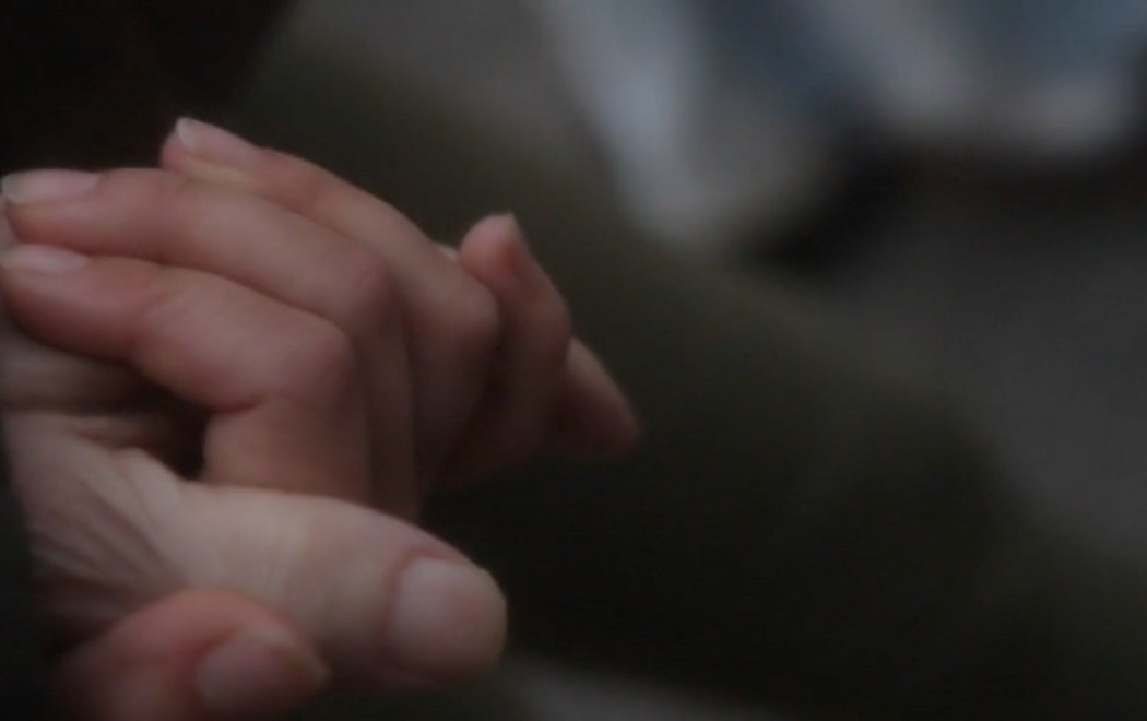 A close up of two people holding hands with a blurred background and dreamlike feel