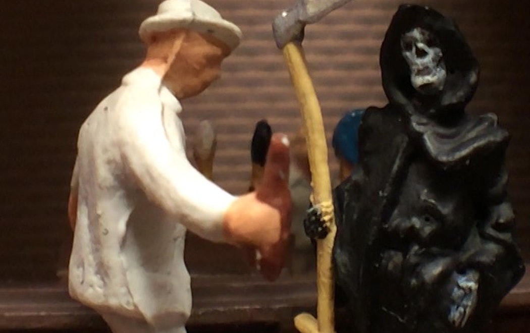 A model of a person in a white hat and suit is talking to a model of the grim reaper