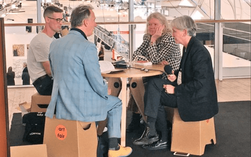 Four people sit around a small table at the airport, having a discussion