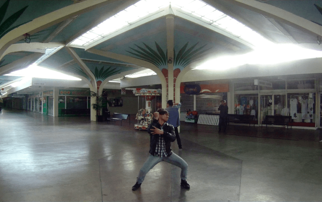 A person dances intensely in an almost empty Mangere Mall