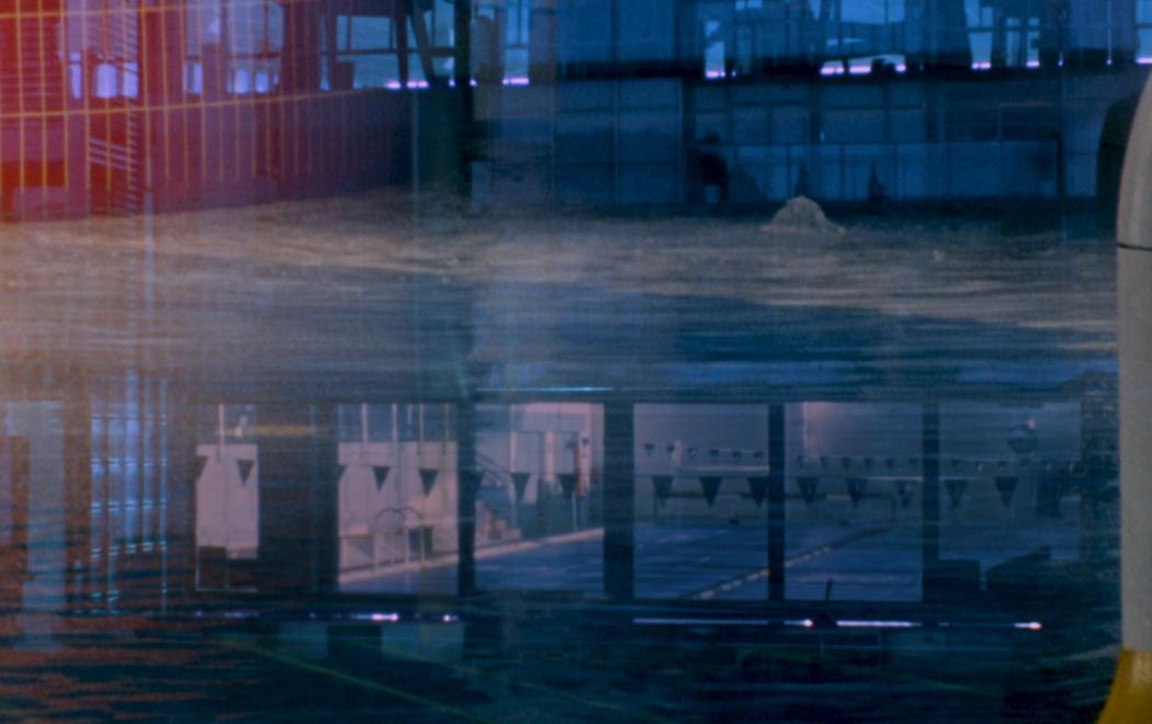 A indoor swimming pool seen through a window with lots of reflections