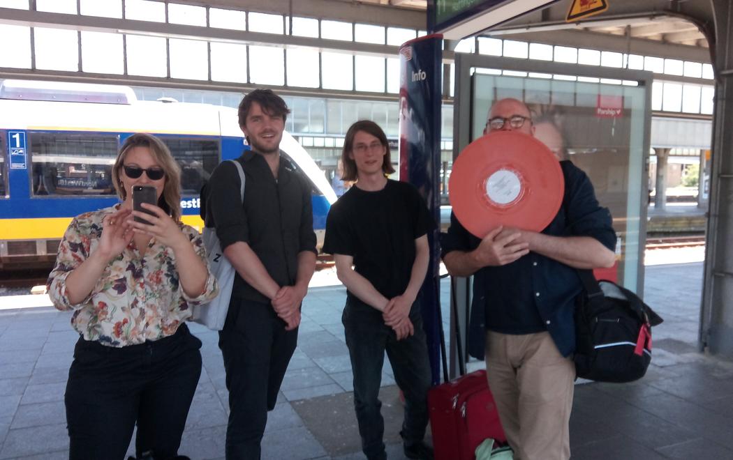 Four people stand smiling at a train station in Germany