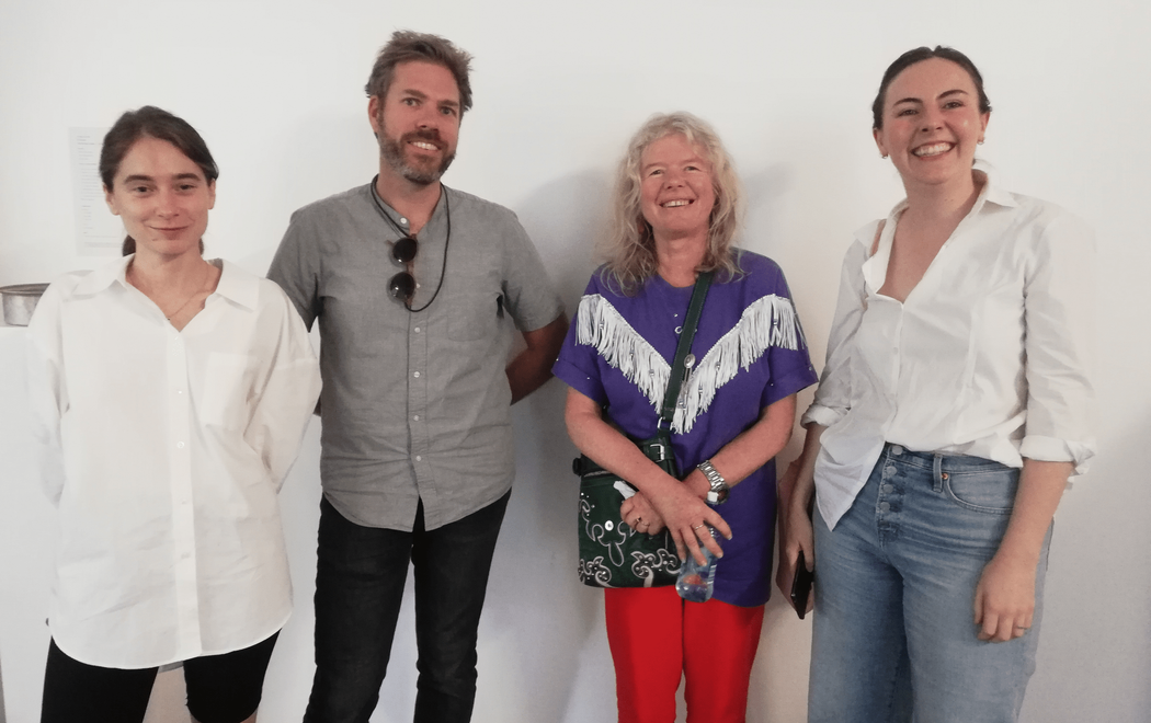 Four people stand smiling brightly, looking happy to be there