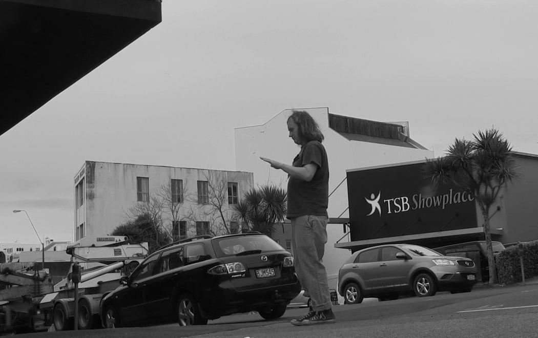 A person stands on the footpath with their eyes closed