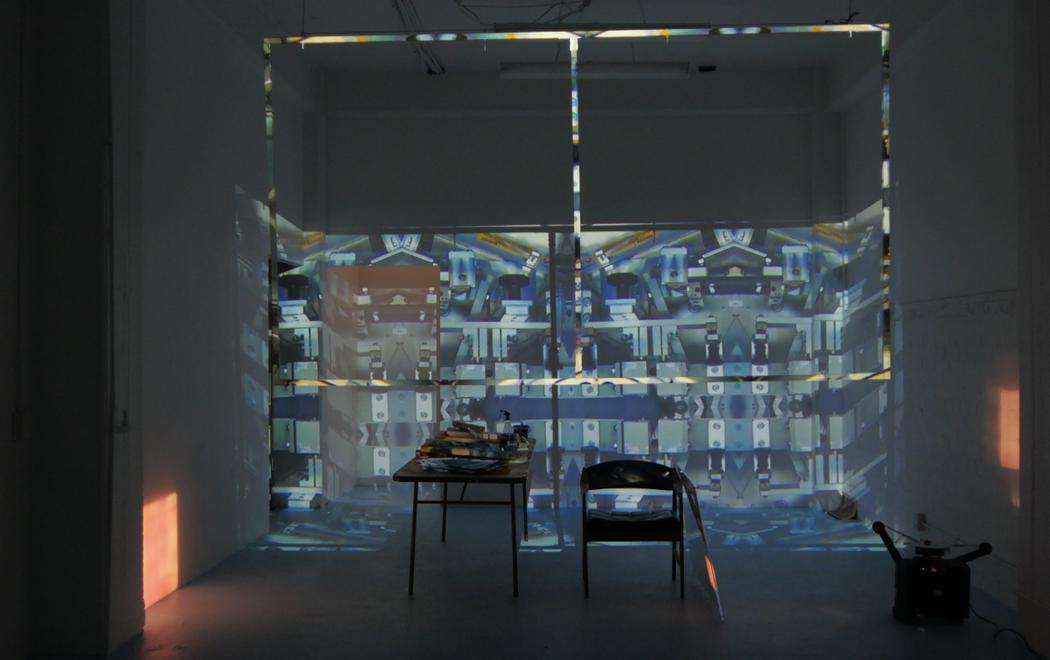 In a dark gallery images are projected onto a table and chairs against a wall