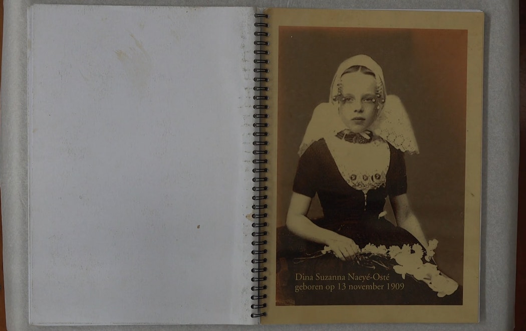 An open phot album showing a young Dutch girl in 1909 wearing ornate and proper dress for the camera