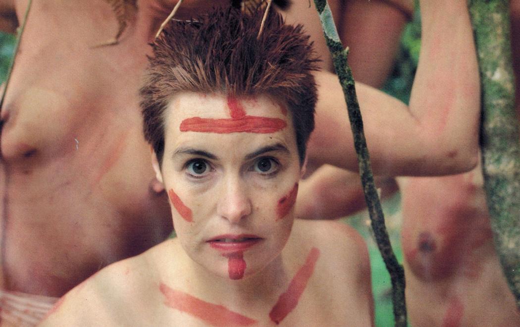 A woman in red face paint stares into the camera.
