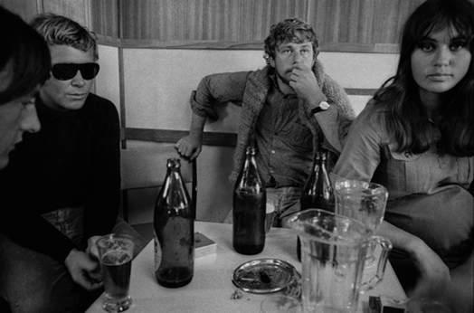 A group of people sit around a table drinking beer crate bottles