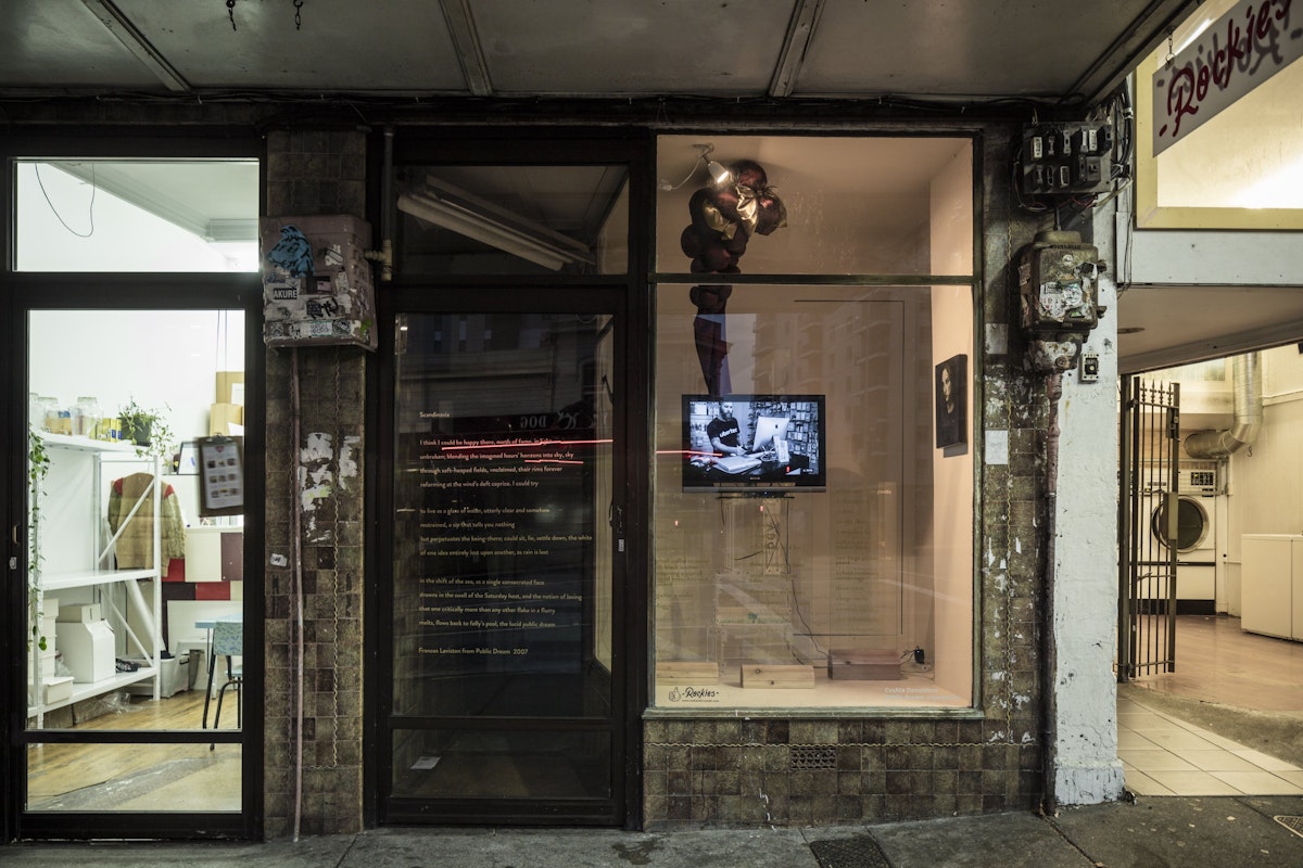 A small gallery in between a laundromat and a homeware store is displaying golden poetry as on the glass and a video work by Cushla Donaldson