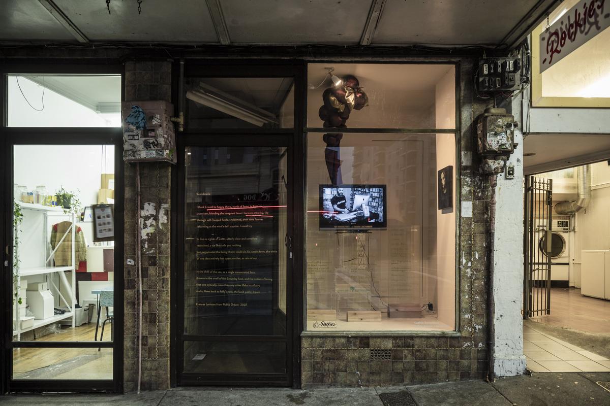 A small gallery in between a laundromat and a homeware store is displaying golden poetry as on the glass and a video work by Cushla Donaldson