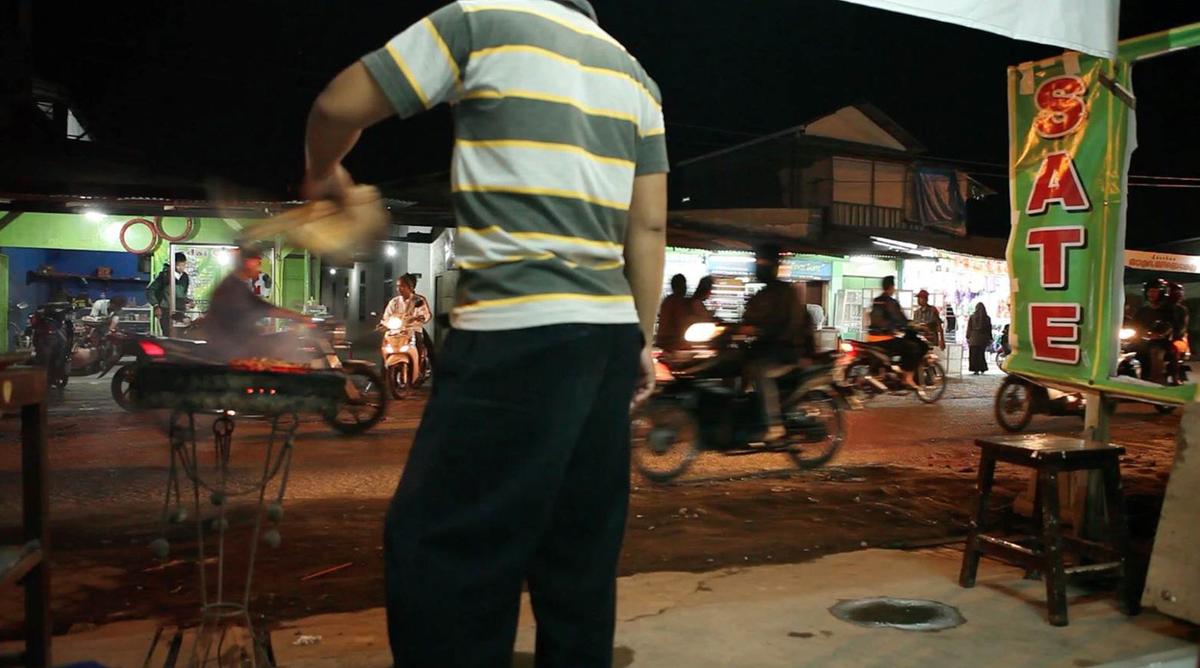 Someone is cooking food near a busy street