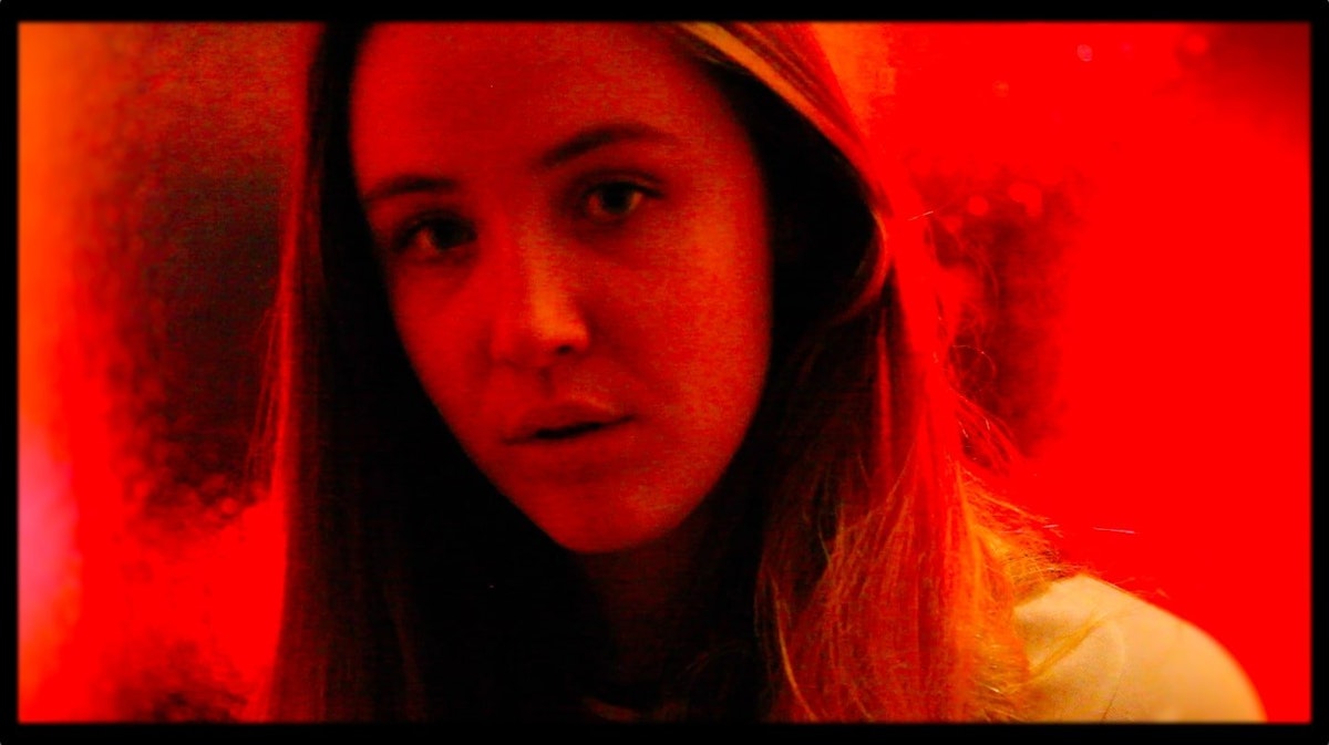 A young person looks innocently at the camera covered in a red hue