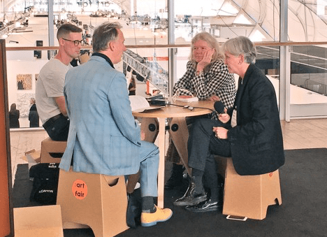 Four people sit around a small table at the airport, having a discussion