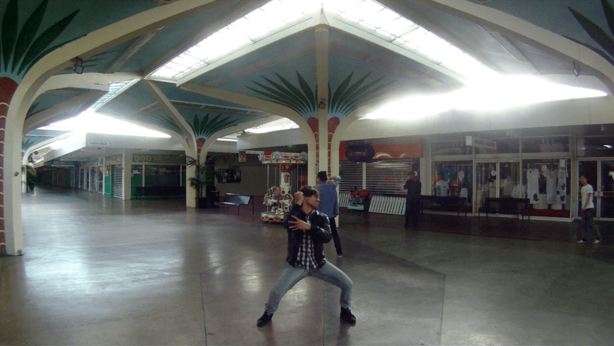 A person dances intensely in an almost empty Mangere Mall