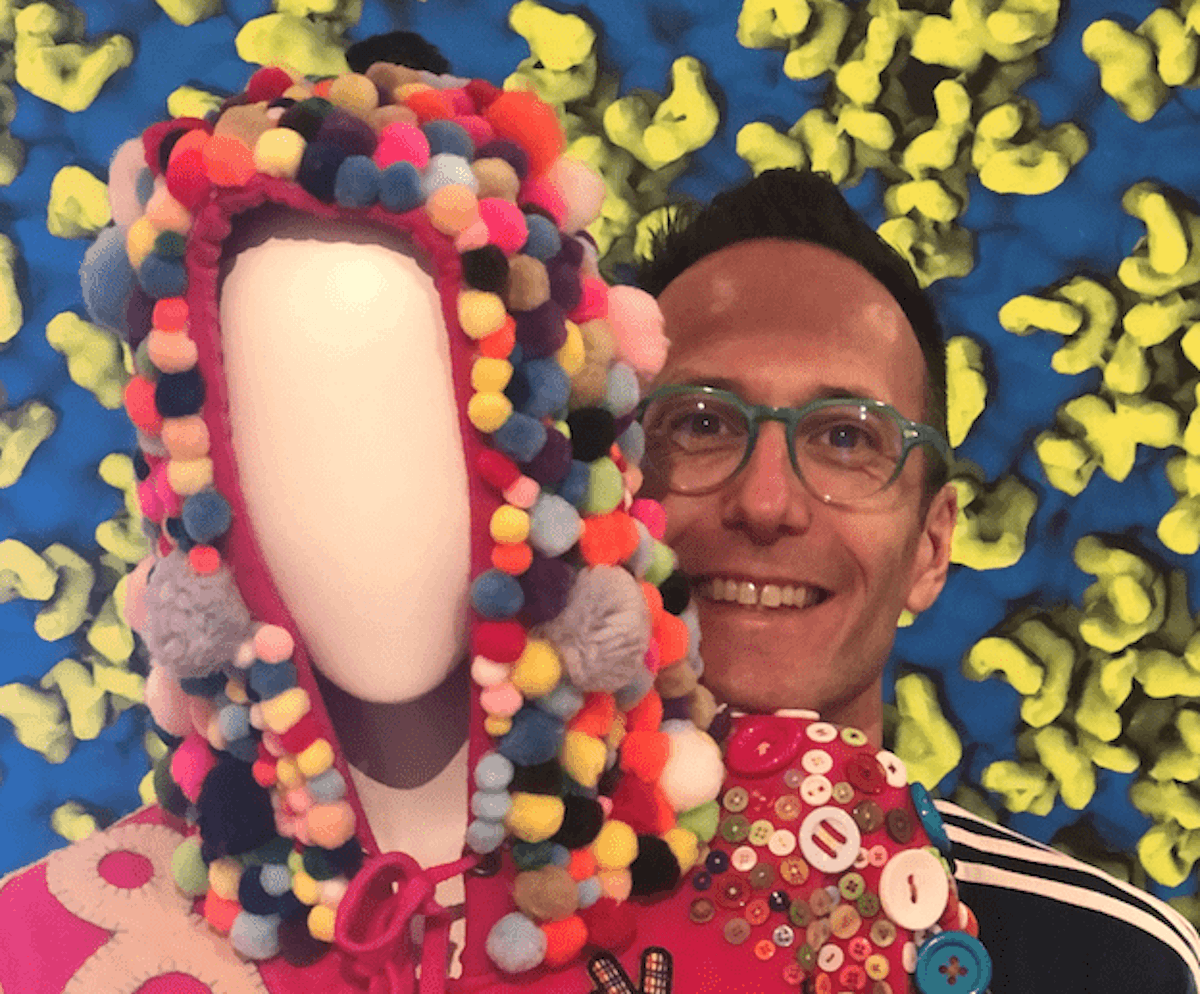 John Walter is smiling standing behind a mannequin dressed in a colourful hand crafted hoodie
