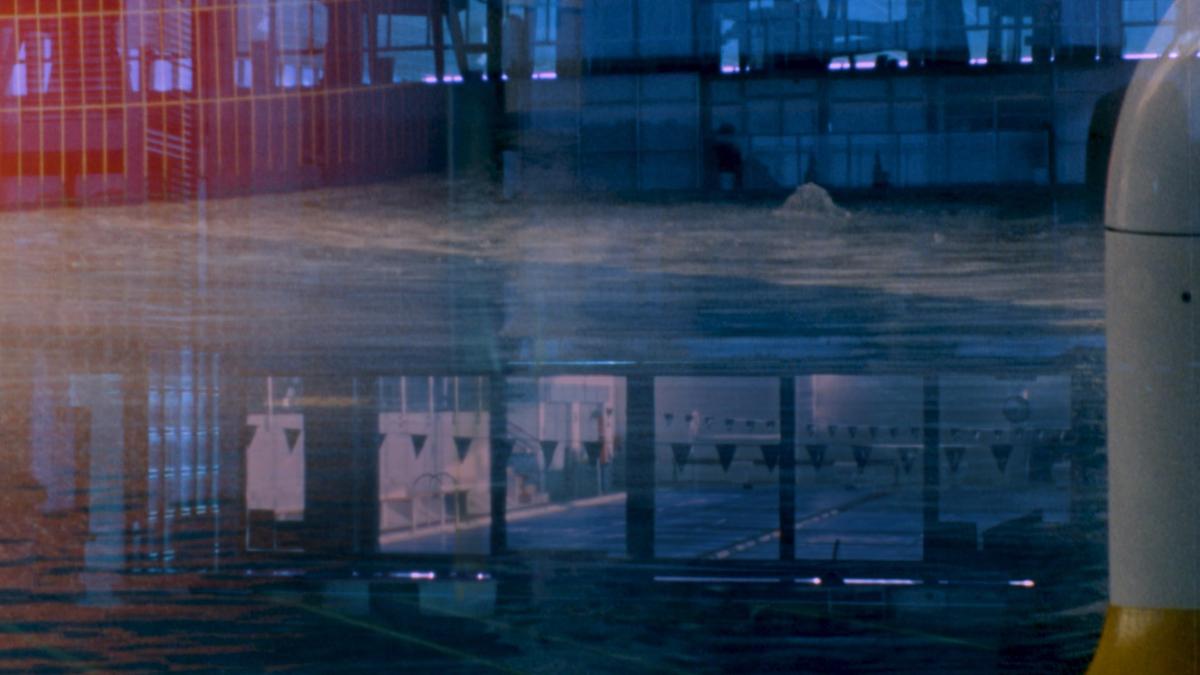 A indoor swimming pool seen through a window with lots of reflections