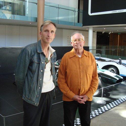 Podcast host Mark Amery standing next to interviewee and artist Billy Apple. Behind them we glimpse the nose of a vintage racing car.