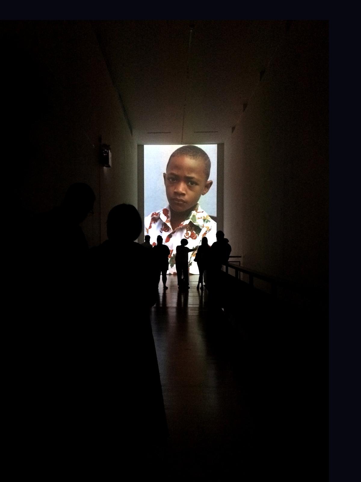 Silhouettes against a portrait orientated projection at the end of a long hallway