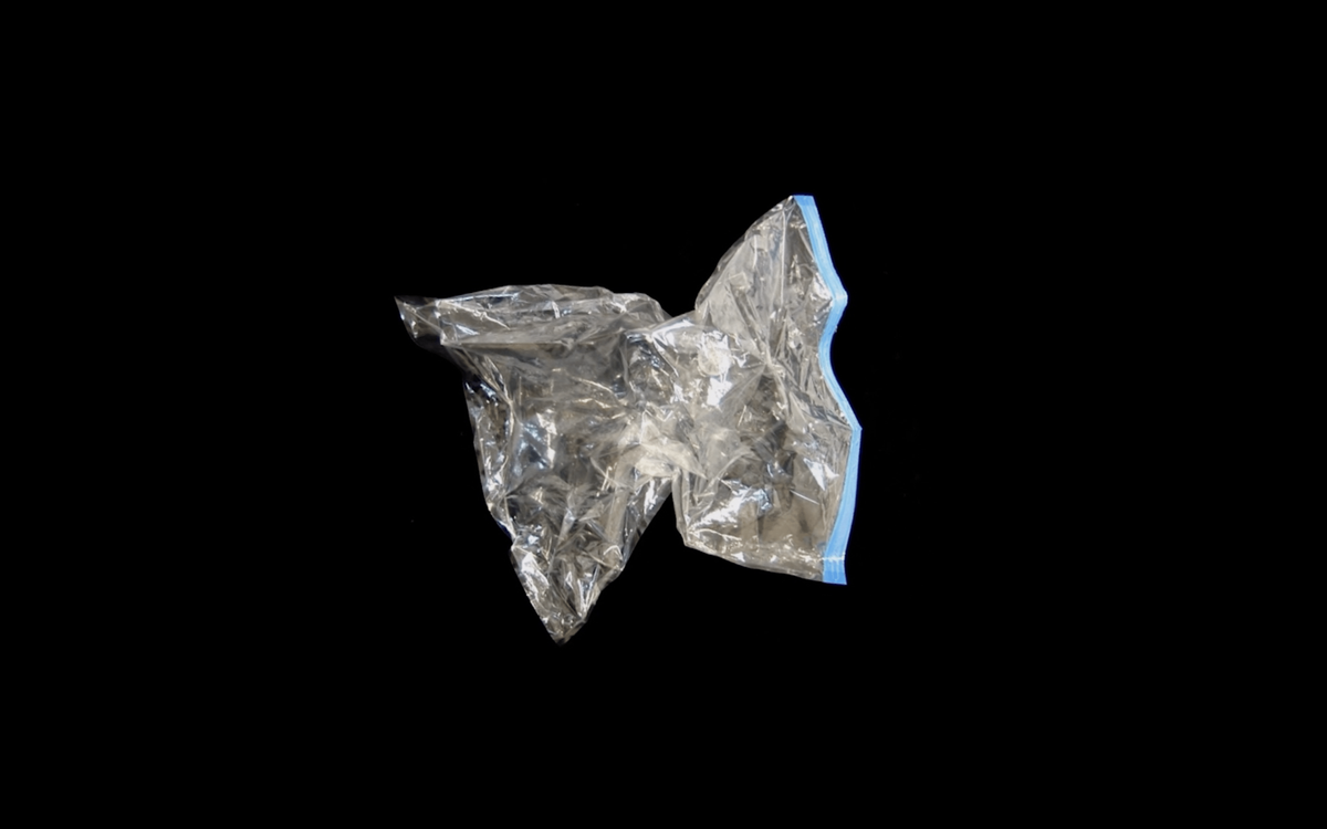 An empty silver wine bladder contracts into a star-like shape as if the air has been sucked out of it. The background is black, which makes the wine bladder appear to float in space.