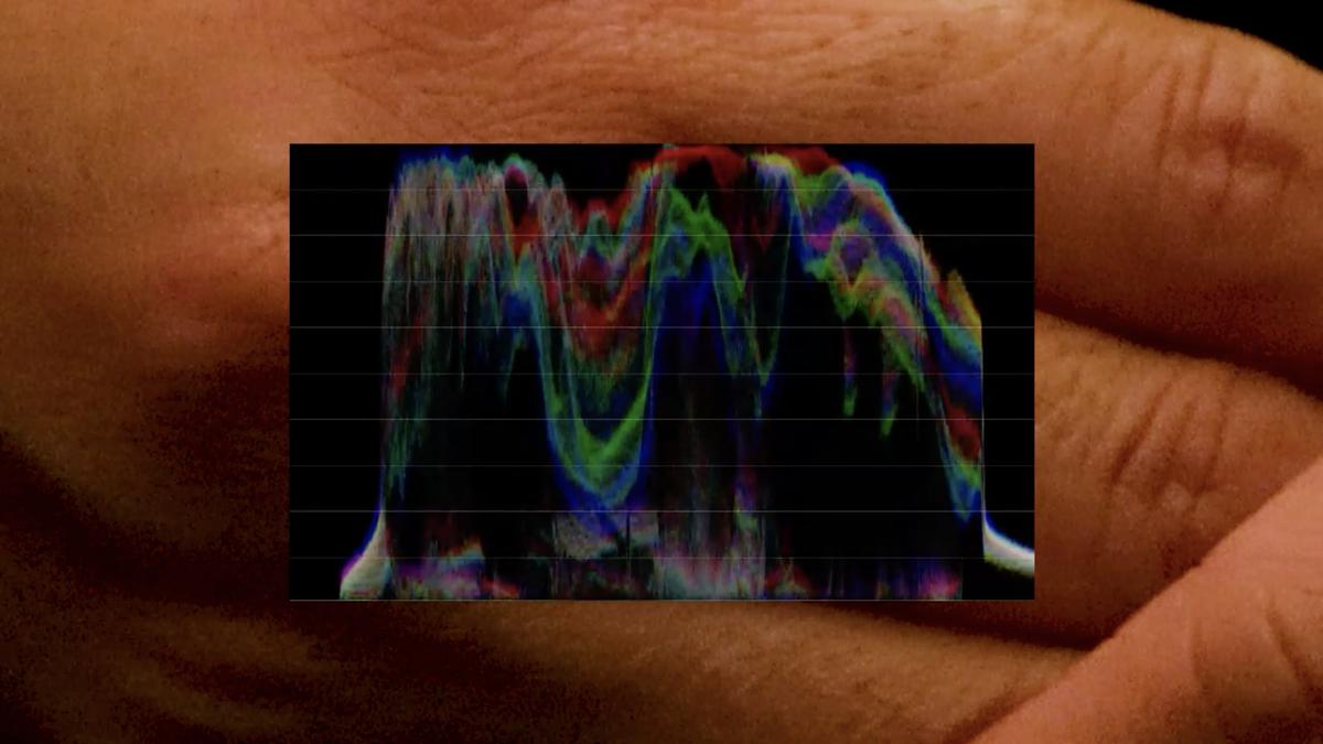 A colourful digital wave form is overlaid on a hand, two types of imagery brought together in one frame, one abstract data, the other photo realistic.