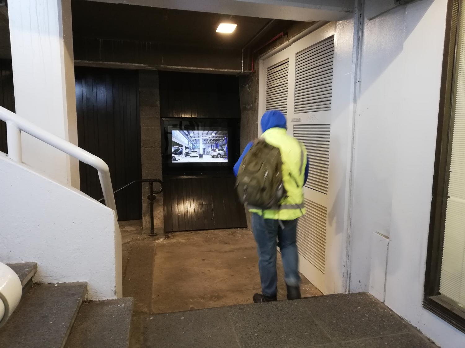 A worker in fluorescent vest watches a video installed in Masons Screen.