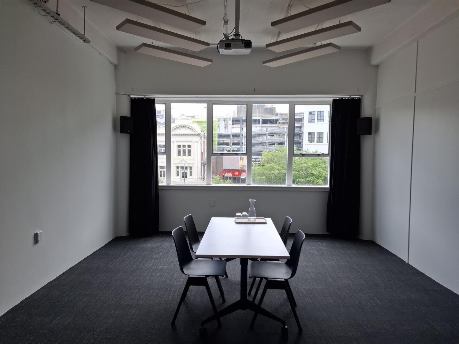 An empty gallery with a board room table. curtains and a view to the street