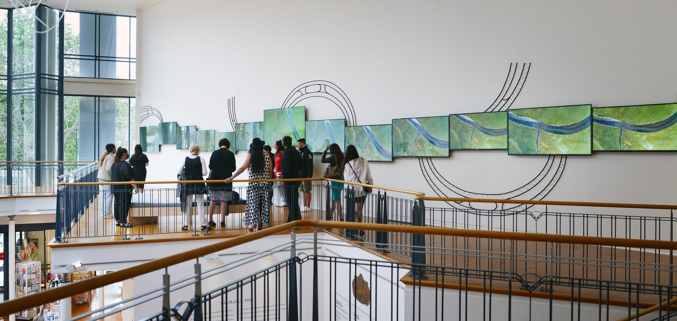 Installation view of 12 TV screens on walls near a balcony