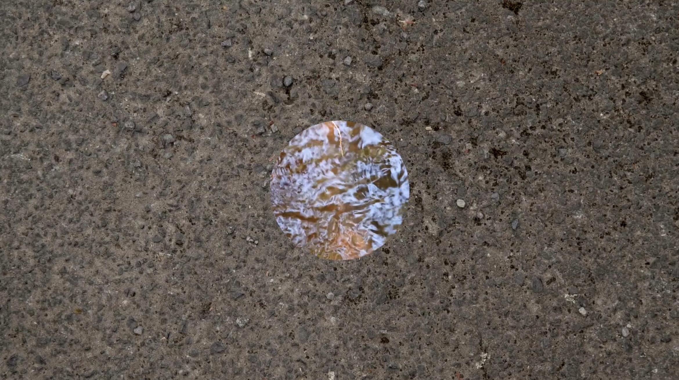 In a concrete wall we see a circle which shows a watery reflective surface.