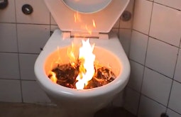 A fire burns inside a toilet bowl.