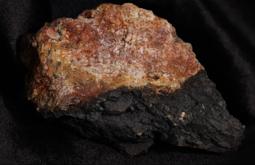 A still of a rock, its surface is red and brown, the colour of rust.