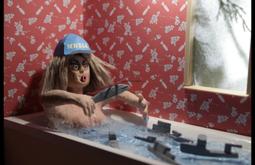 An animated still of a woman sitting in a bathtub playing with military vehicles. The wallpaper alternates pictures of bombs and roses.