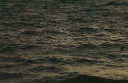 The sea at dusk, small caps appear on the waves.