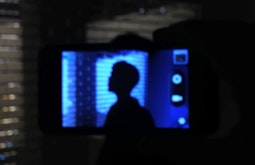 A persons head is seen silhouetted on a camera's screen. They are surrounded by blue light.