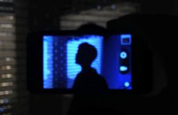 A persons head is seen silhouetted on a camera's screen. They are surrounded by blue light.