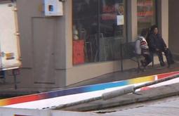 Two people sit outside a bakery on a grey day.