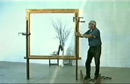 A person attaches clamps to a large empty picture frame