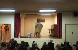 A person stands on stage making an outfit out of cardboard boxes.