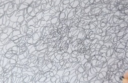 A hand draws endless circles in pencil.