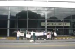 A group of people hold signs outside the Amora hotel.