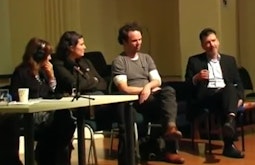 Four people sit in a panel having a public conversation.