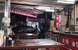 An empty restaurant in Taipei, there are chopsticks and condiments on each table. A glossy black car drives past.