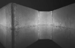 A block of ice on a reflective surface is illuminated from behind.