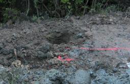 Turned over earth and rocks with a red spray-painted line running through.