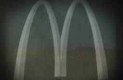 The McDonalds arches are overlaid on an image of a rural desert road and landscape.