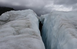 A person walks in the crevice between two icebergs.
